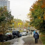 Autumn street with cars and a pedestrian