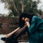 woman in blue long sleeve shirt and black pants sitting on brown wooden dock during daytime